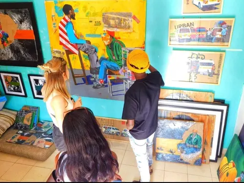 Visitors at an art fair looking at framed matatu paintings hung on a teal wall