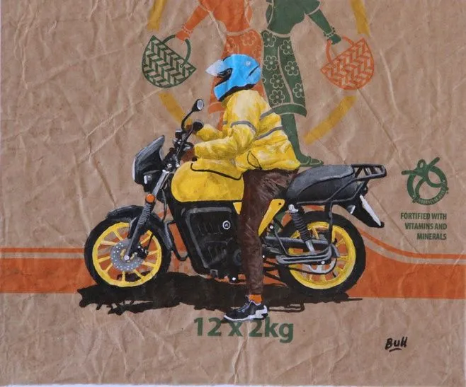 A rider in a yellow jacket and blue helmet on a black motorcycle, painted on brown kraft packaging printed with baskets and the words 12 x 2kg