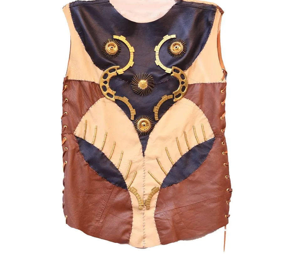 A leather bodice in cream and oxblood panels with two curved brass plates at the chest and a brass rosette below