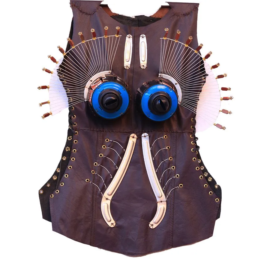 A sleeveless leather bodice with two blue discs at the chest and a fan of pale spikes rising behind the shoulders