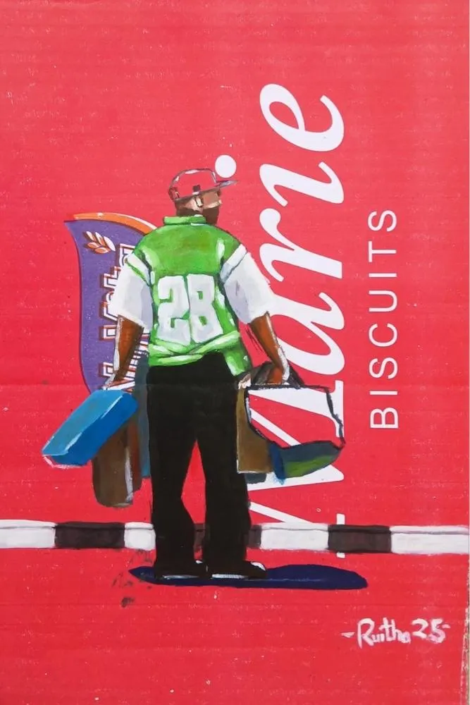 A man seen from behind in a green number 28 jersey, a bag in each hand, standing on a white road line painted across a red Marie Biscuits carton