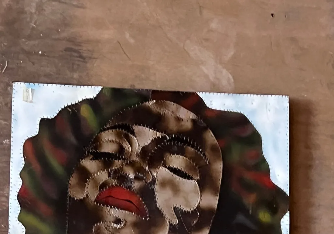 A reclining figure with eyes closed, built from scorched and mottled panels stitched together over a pale backing sheet
